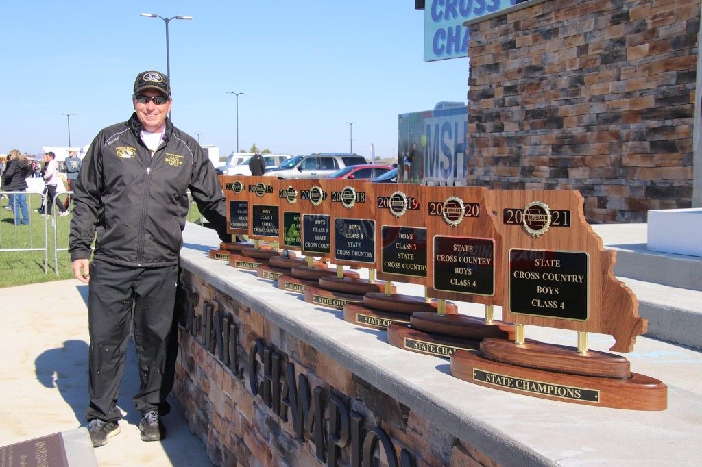 Coach Bryant Wright with eight consecutive Missouri state cross country championship trophies, 2014–2021